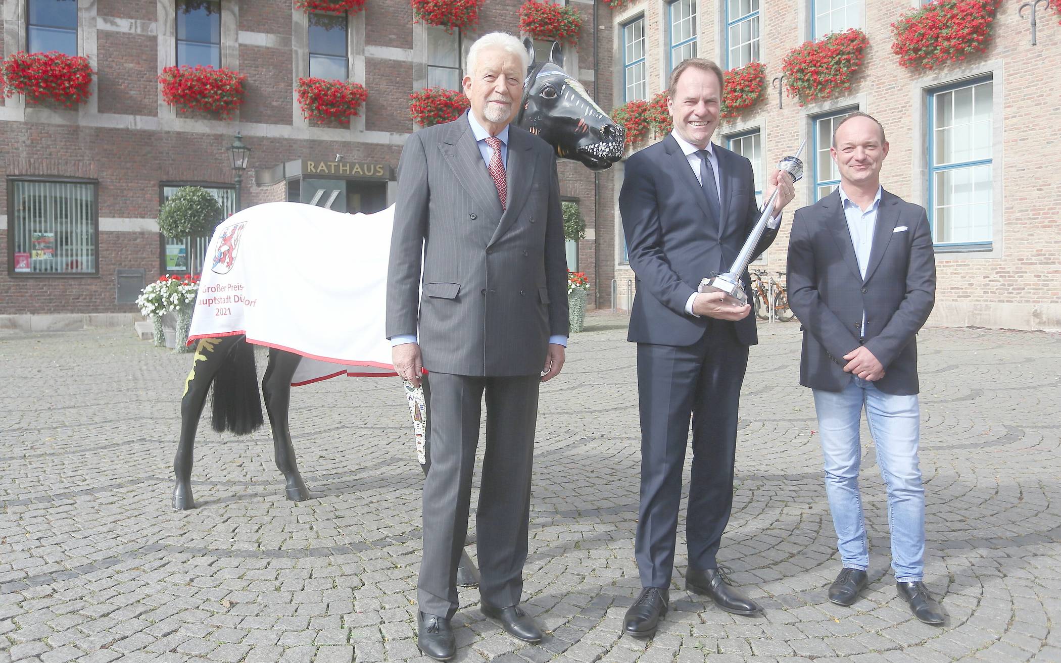  Oberbürgermeister Dr. Stephan Keller (2.v.l.), Peter M. Endres (l.) und Galopp-Trainer Sascha Smrczek präsentieren den Rheinturm für den Gewinner der 101. Auflage des "Großen Preises der Landeshauptstadt". 