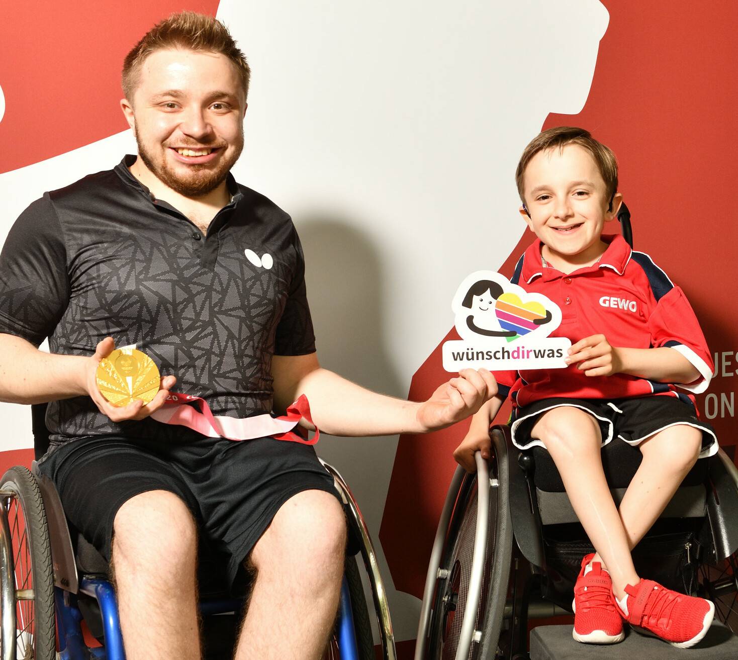  Para-Olympiasieger Valentin Baus (l.) zeigt seinem jungen Besucher und Fan Moritz seine Goldmedaille von Tokio. 