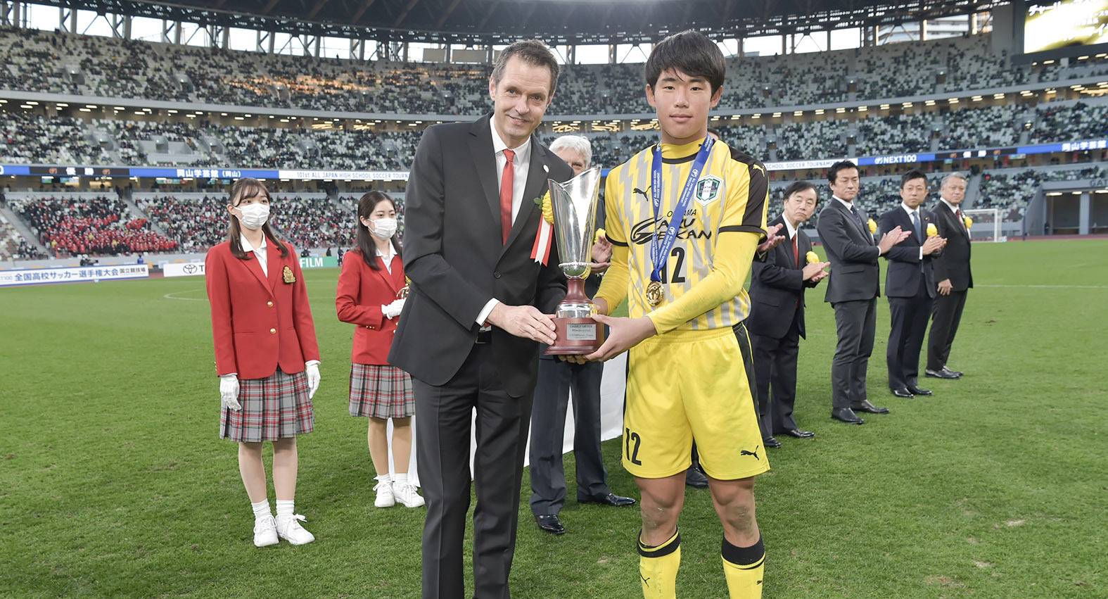 Osterturnierleiter Martin Meyer übergibt dem Kapitän der siegreichen Japanischen Hochschulmannschaft im Stadion in Tokio den nach seinem Vater „Charly“ benannten Pokal.