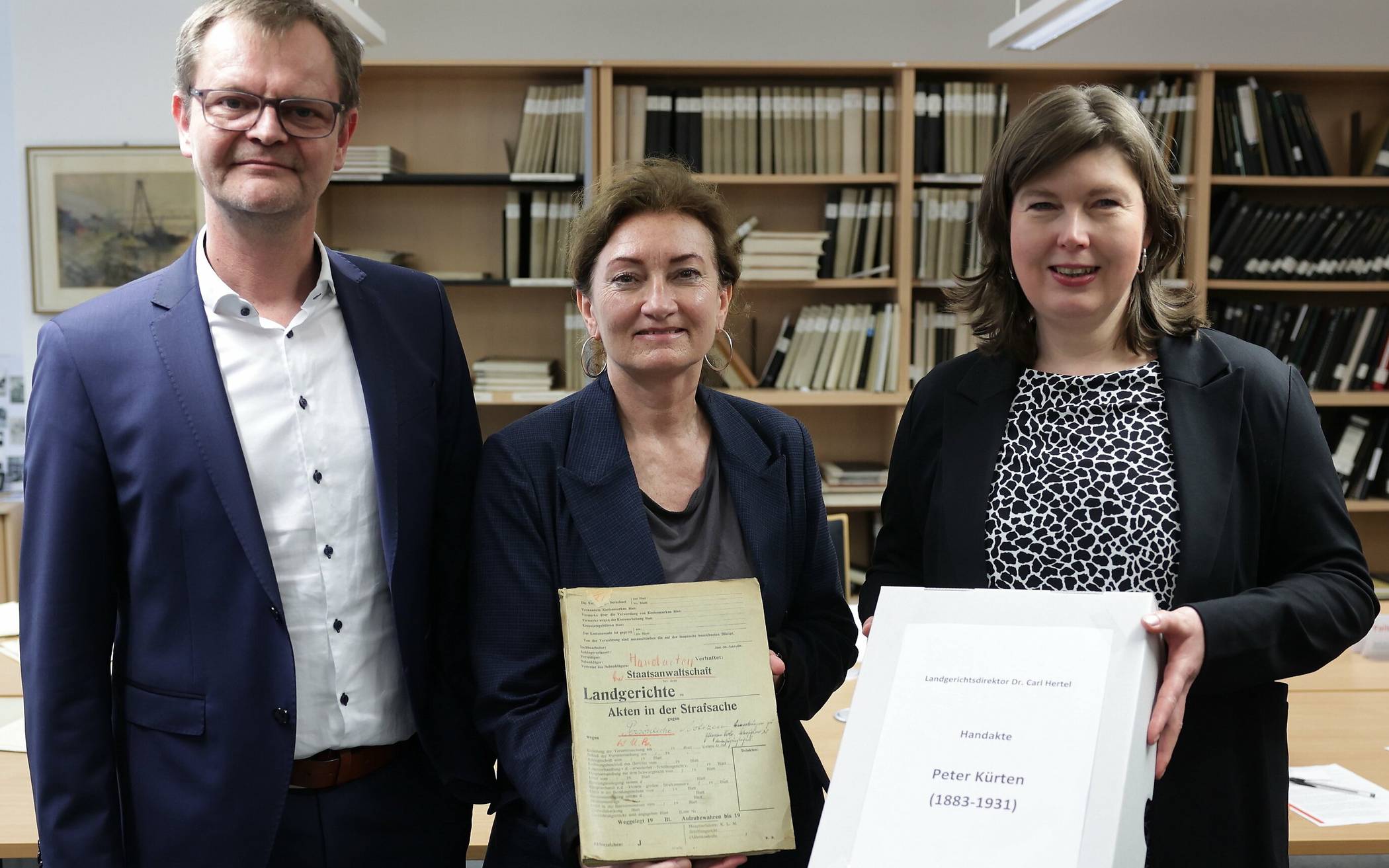 Die Kultur-Beigeordnete Miriam Koch (m.) und Dr. Benedikt Mauer, Leiter des Stadtarchivs, bei der symbolischen Übergabe der „Handakte“ Peter Kürten an Dr. Martina Wiech, vom NRW-Landesarchiv.