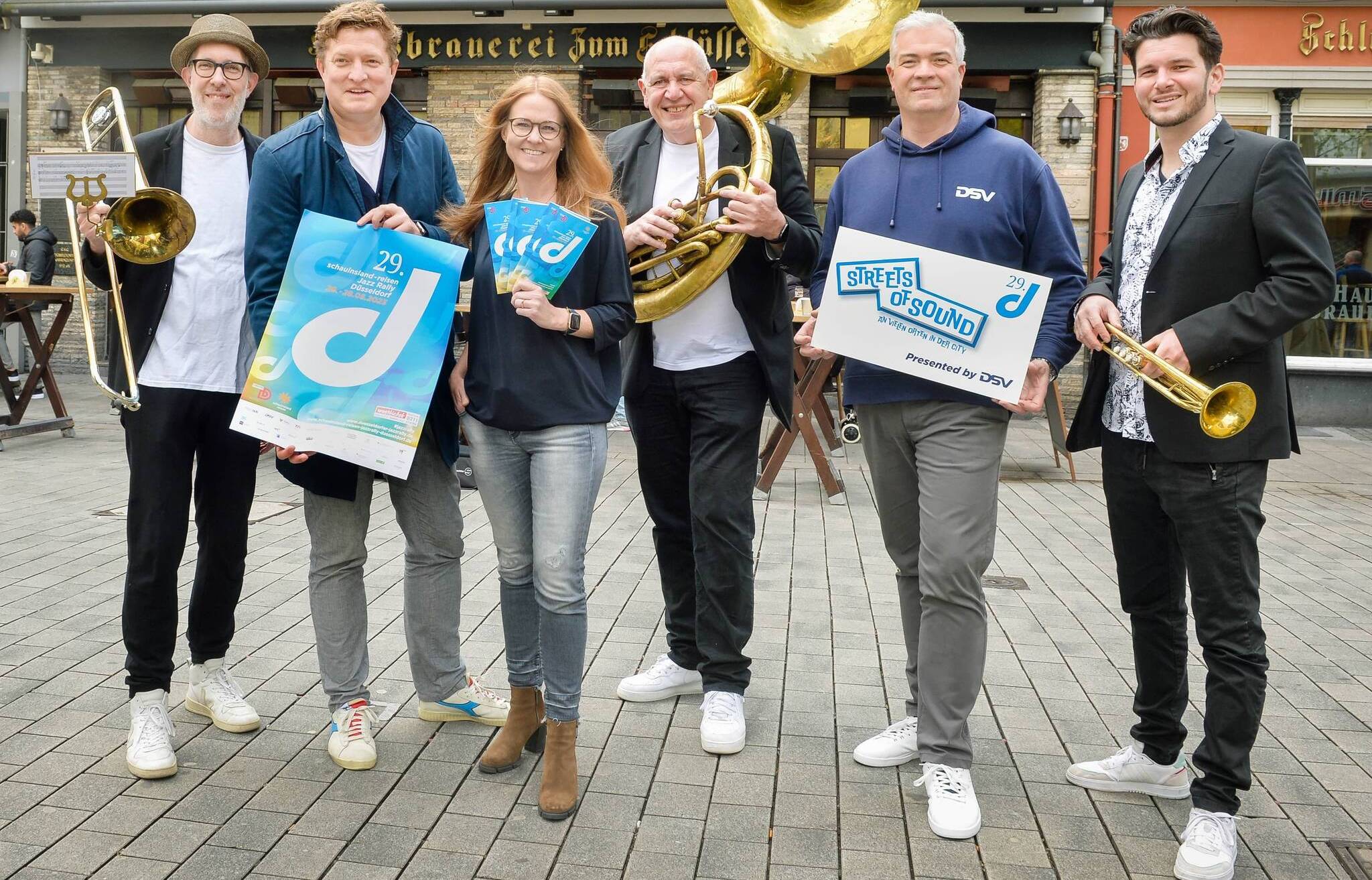 Destination-Geschäftsführer Thomas Kötter (2. v. l.), Altstadt-Gastronomin Kerstin Rapp-Schwan und „Street of Sound“-Präsentator Markus Walke (2. v. r.) mit Musikern der Marching Band „Martin Reuther Swing Unit“.