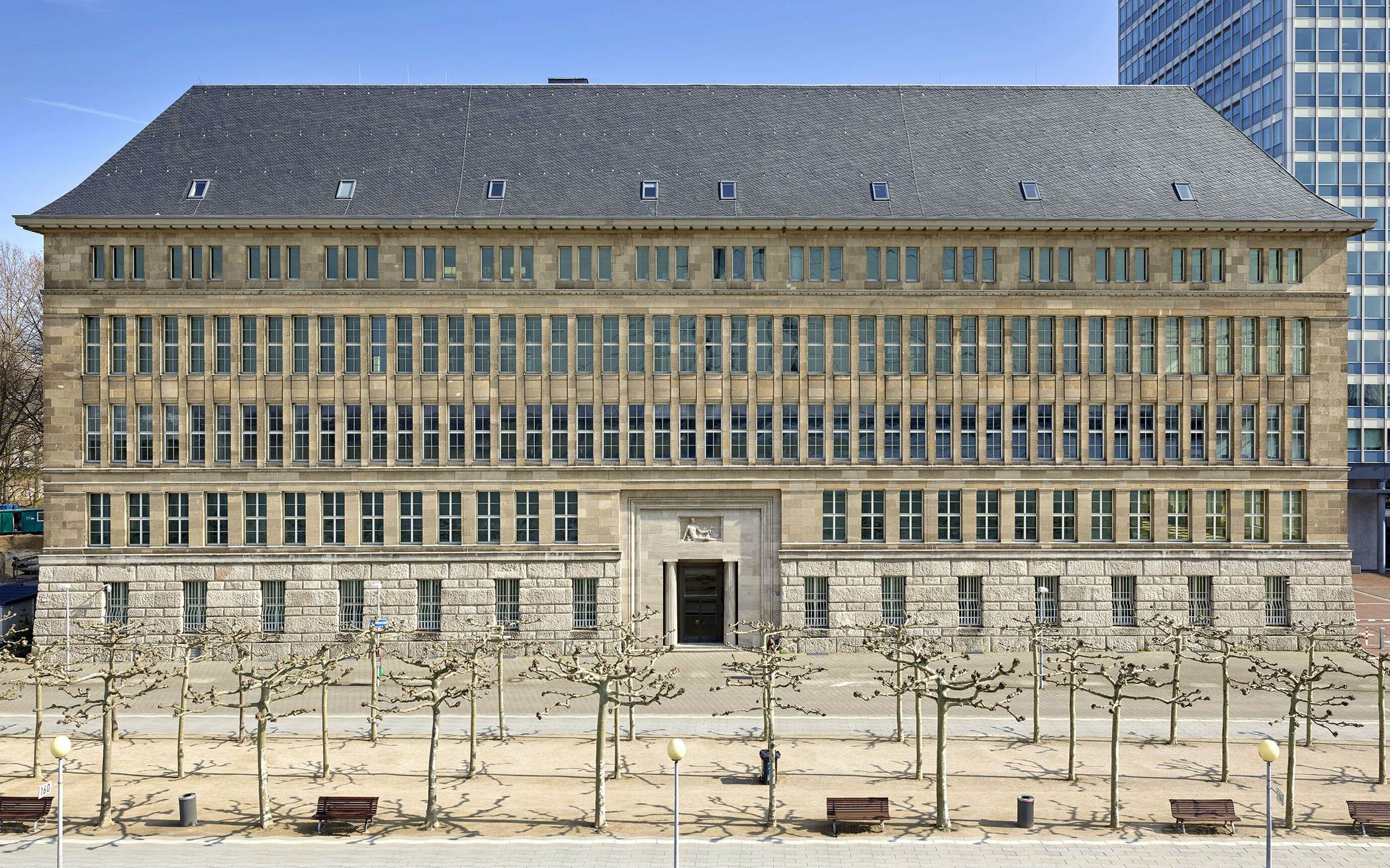  Die Behrensbau-Fassade am Rheinufer. Die Fassade kommt fast ohne Dekoration aus, auffällig ist der Rhythmus der vielen rechteckigen Fenster. 