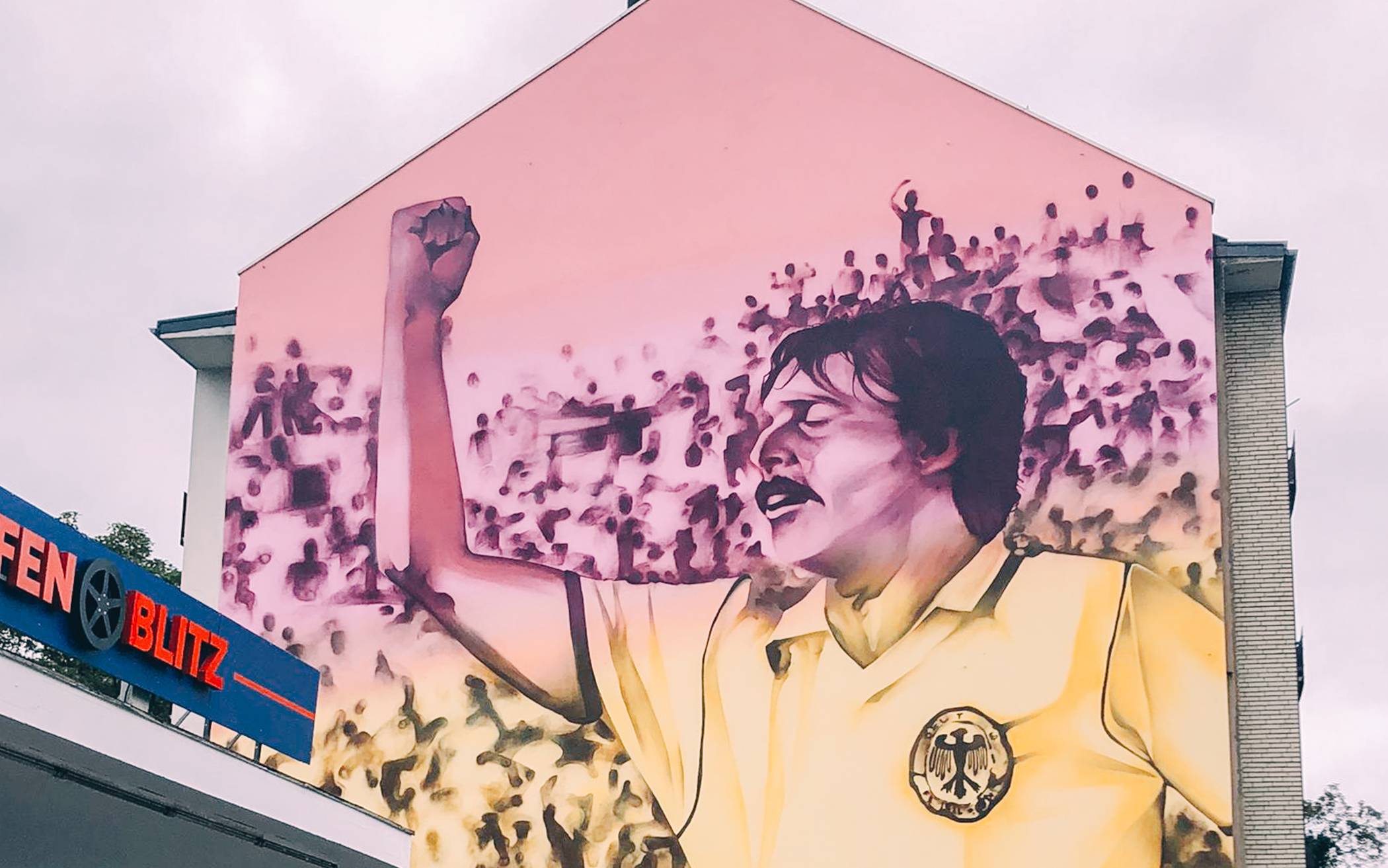 Die Kunst-Wandmalerei, oder „Mural“, des Künstlers Damian zeigt Klaus Allofs auf einem Gebäude an der Cranachstraße 52 - in Jubelpose bei der EM 1980...