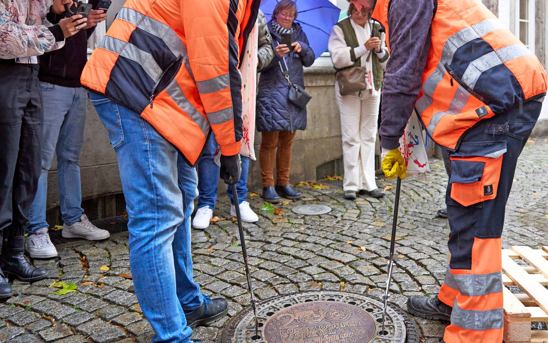 SEBD-Mitarbeiter setzen den Karnevals-Kanaldeckel ein.