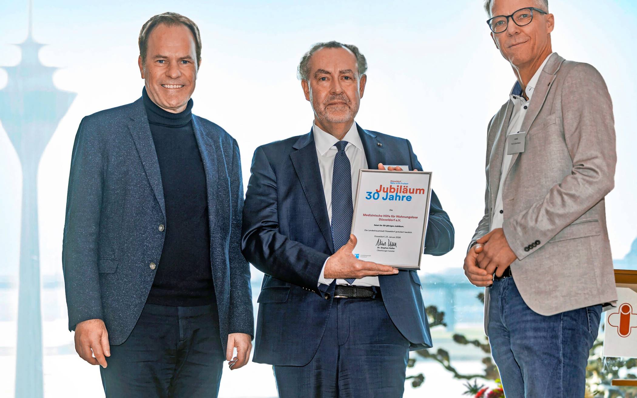   Dr. Stefan Reuter (r.), ist Vorsitzender des Vereins für Medizinische Hilfe in Düsseldorf, Dr. Carsten König (m., mit Jubiläumsurkunde, überreicht von OB Stephan Keller) Mitstreiter der ersten Stunde.   