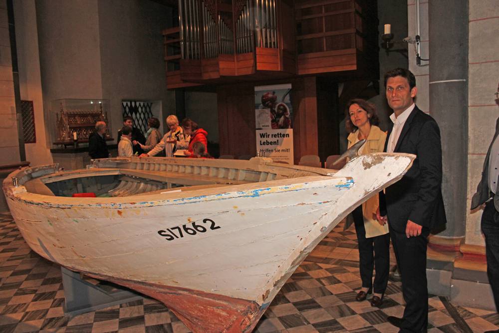  Christian Ehring steht zusammen mit Angelika Fröhling neben dem Flüchtlingsboot, das die Diözese der Kirchengemeinde für die Veranstaltungen in dieser Woche überlassen hat, bevor es ins Bonner Haus der Geschichte transportiert wird. 