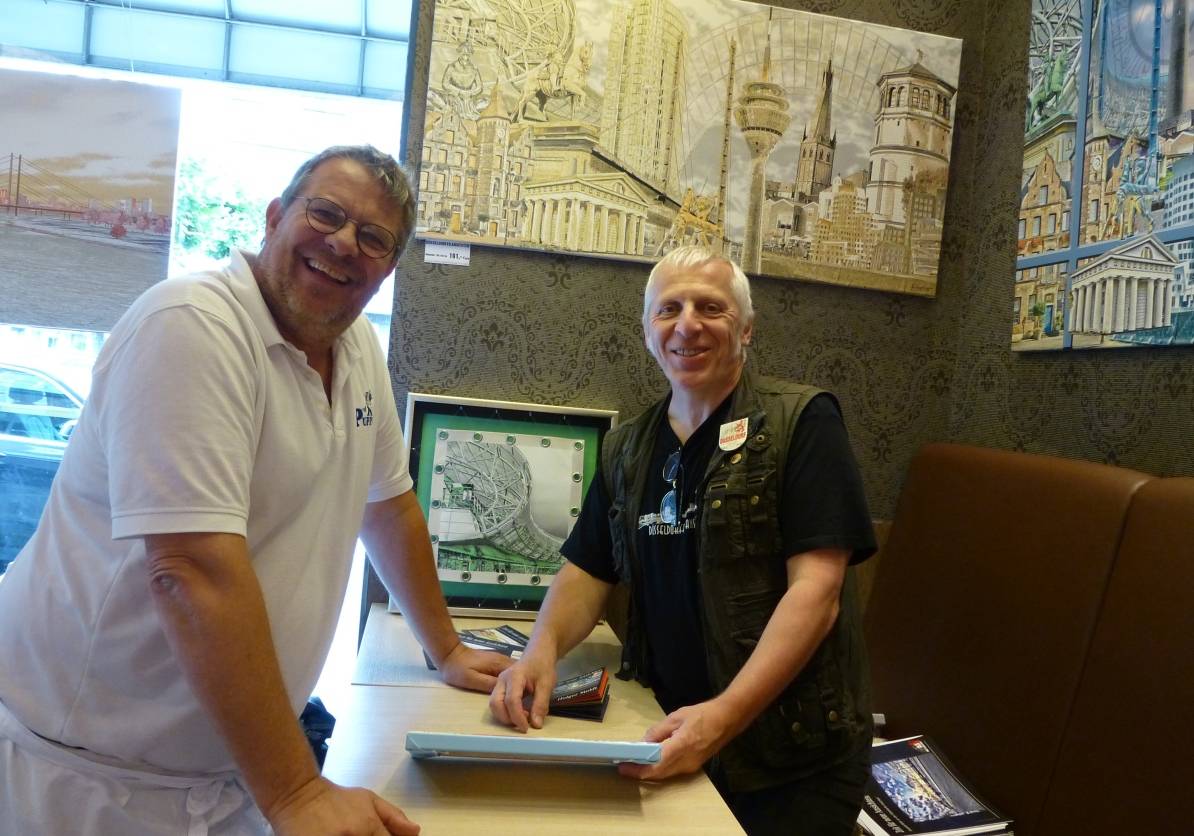  Bäckermeister Thomas Puppe (li.) freut sich, dass Holger Stoldt seine Düsseldorfer Ansichten bei ihm ausstellt. "Das ist bezahlbare Kunst mit einem hohen Maß an Individualität und Liebe zur Stadt." 