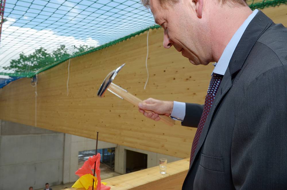  Stadtdirektor Burkhard Hintzsche schlägt den symbolisch letzten Nagel ins Holz der neuen Halle am Tischtenniszentrum. 