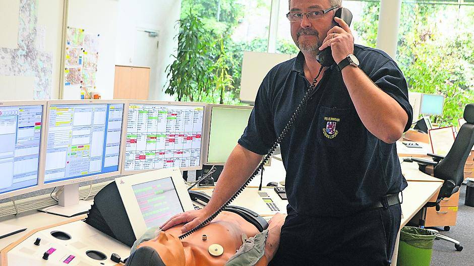  Dieter Mandel von der Düsseldorfer Feuerwehr posiert in der Leitstelle mit einer Puppe, an der die Feuerwehr für gewöhnlich die Erste Hilfe übt. Wenn der erfahrene Retter am Telefon bei Notfällen Anweisungen für die Wiederbelebung gibt, ist sie natürlich nicht dabei. 