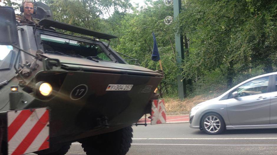 Bürger am Straßenrand und Soldaten gucken sich...
