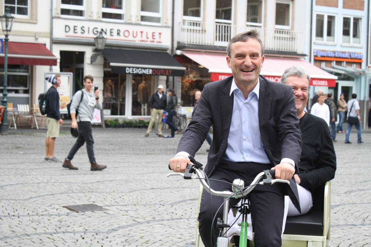  Die Fahrrad-Rikscha kann man am Samstag ersteigern. Der gewählte Oberbürgermeister Thomas Geisel (l.) und der Auktionator Manes Meckenstock wagen eine Probefahrt. 
