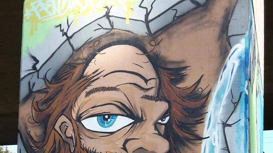 Mit witzigen Graffitis an den Pfeilern der Autobahnbrücke. Der Neandertaler ist...