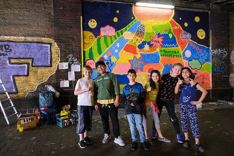  Malaktion an der Unterführung Hüttenstraße: Das neue Wandbild mit sechs der an der Aktion beteiligten Kindern: (v. l.) Leonard, Jawad, Diyar, Fotini, Marika und Luna. 