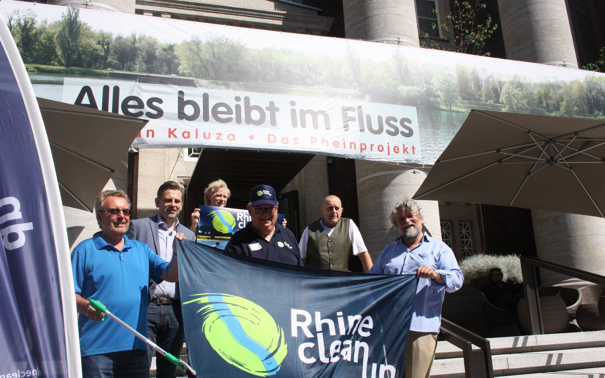  Die Rhine Clean up-Organisatoren vor der am Medici-Hotel befindlichen Fotoinstallation des Künstlers Stephan Kaluza (2. v. r.). „Alles bleibt im Fluss - der Rhein“ ist 100 Meter lang, 2,5 Meter hoch und ist aus 21449 Einzelbildern technisch zusammengefügt worden. 