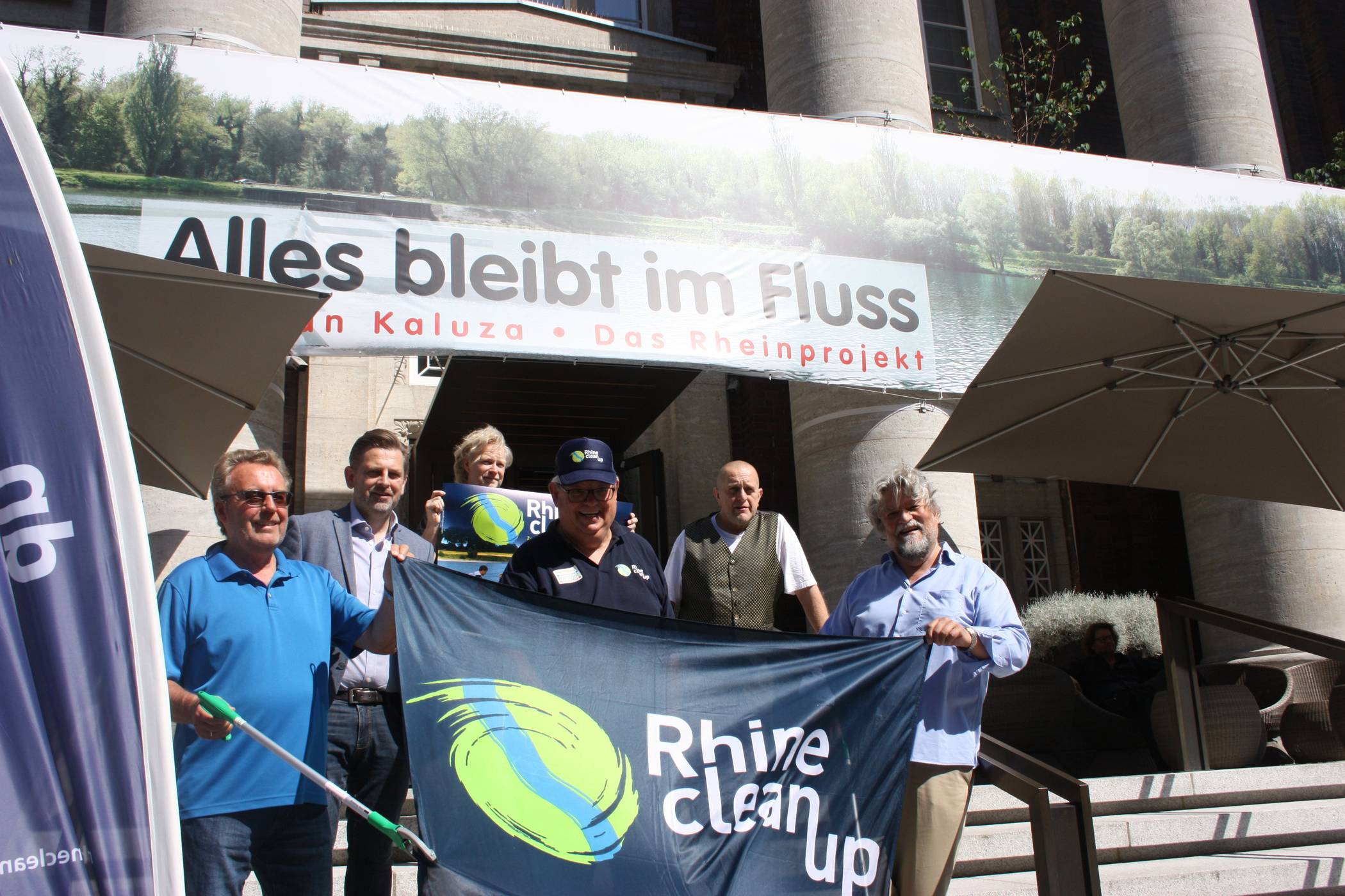  Die Rhine Clean up-Organisatoren vor der am Medici-Hotel befindlichen Fotoinstallation des Künstlers Stephan Kaluza (2. v. r.). „Alles bleibt im Fluss - der Rhein“ ist 100 Meter lang, 2,5 Meter hoch und ist aus 21449 Einzelbildern technisch zusammengefügt worden. 