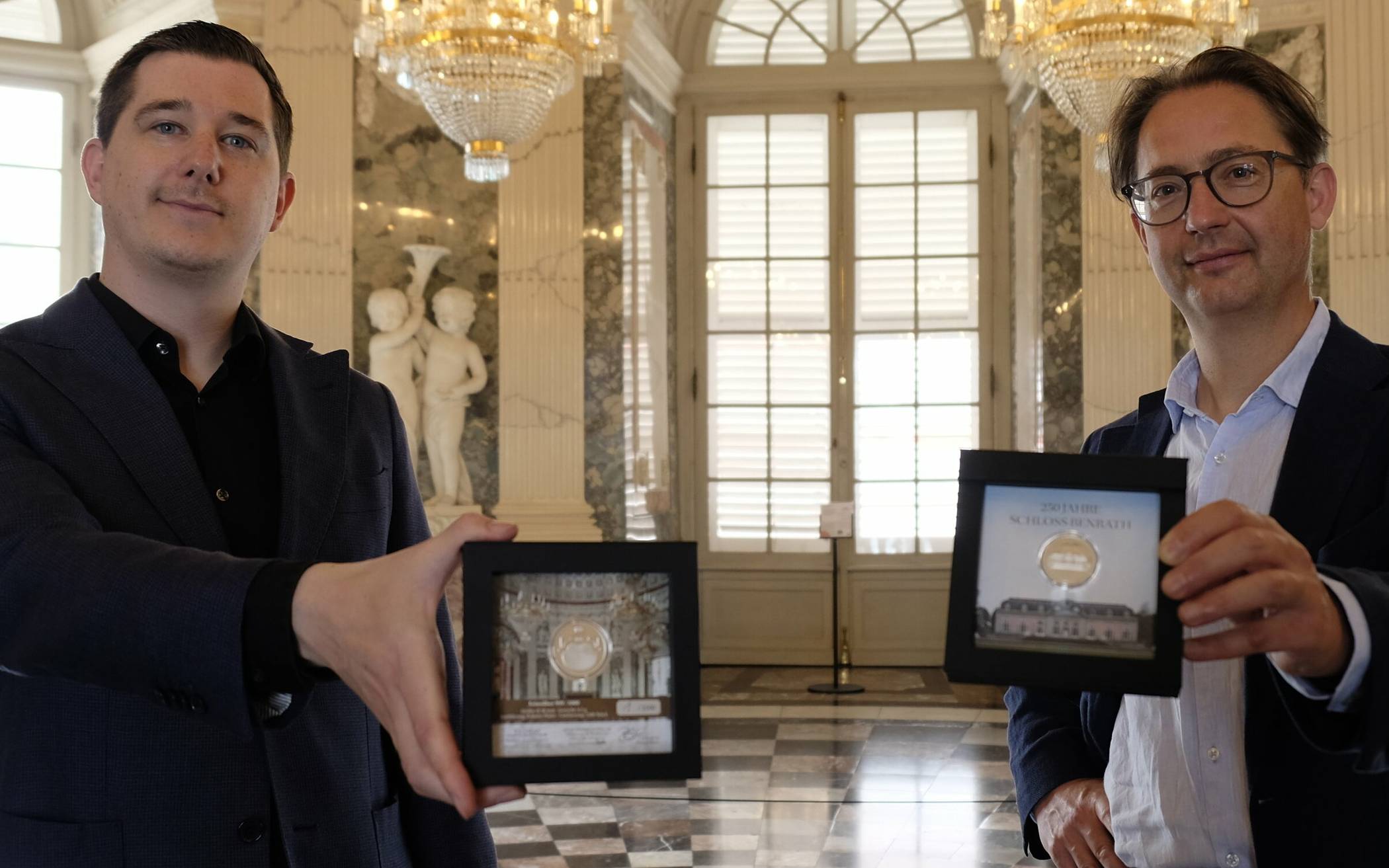  Schloss-Stiftungs-Vorstand Prof. Dr. Stefan Schweizer (r.) und Lars Knevels von der Münz-Gesellschaft EuroMint präsentieren die Sonderprägung. 